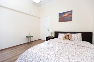 a white bedroom with a large bed with a black headboard at Aladdin's Hostel in Larnaka