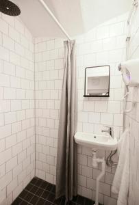 a white tiled bathroom with a sink and a mirror at Old Town Stay Hostel in Stockholm