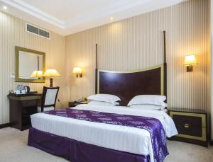 ドーハにあるTourist Hotelの大きなベッドとデスクが備わるホテルルームです。