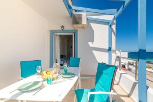 un comedor con una mesa blanca y sillas azules en Filia Apartments, en Milatos