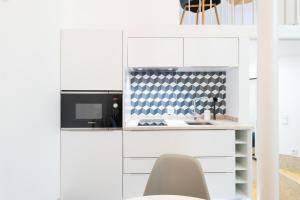 una cucina con armadi bianchi, forno a microonde e sedia di FLH Graça Lovely Apartment II a Lisbona