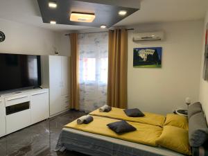 a bedroom with a yellow bed and a flat screen tv at Studio DAMA blizina amfiteatra i bus kolodvora ,privatan parking ,Self-Check- In in Pula