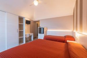 una camera d'albergo con due letti e una televisione di Hotel Danio Lungomare ad Alassio
