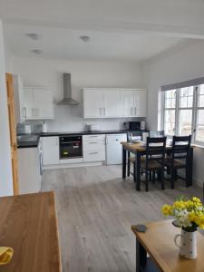 a kitchen with white cabinets and a table and chairs at 1 Golf Mews in Ballater