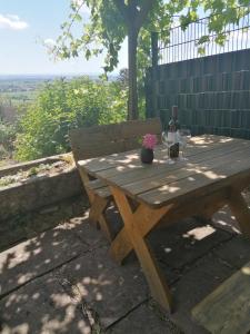 a wooden picnic table with a bottle of wine and flowers on it at Weinstrassenblick in Burrweiler