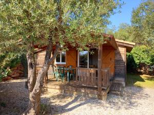 a wooden cabin with a table and a tree at Les chalets du Relais d'Aguilar in Tuchan