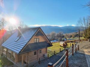 une petite maison avec un toit en métal sur un champ dans l'établissement Babiogórska Chata - dom z bali z jacuzzi i sauną, à Zawoja