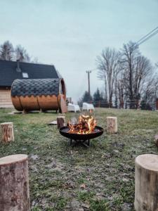 una parrilla con fuego en medio de un campo en Babiogórska Chata - dom z bali z jacuzzi i sauną, en Zawoja