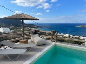 a swimming pool with two chairs and an umbrella at Deja Blue Villa 1 in Agios Georgios