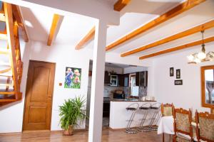 eine Küche und ein Wohnzimmer mit weißen Wänden und Holzbalken in der Unterkunft Casuta-Lacului in Unciuc