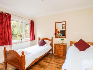 a bedroom with two beds and a mirror at Queen's Cottage in Colwyn Bay