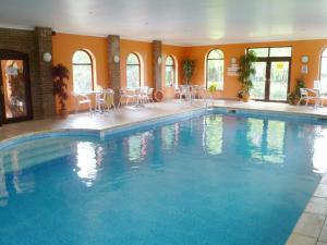 a large swimming pool with chairs and tables in a building at Archways-e1223 in Winthorpe