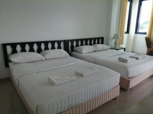 2 łóżka w pokoju hotelowym z ręcznikami w obiekcie มุก&พลอย เรสซิเดนซ์ w mieście Sattahip