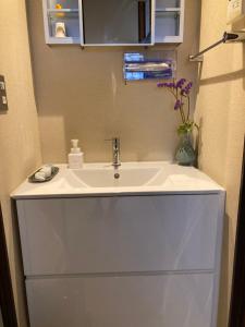 a white bathroom sink with a vase of flowers at Kitazawa Cozy House in Tokyo +37 photos