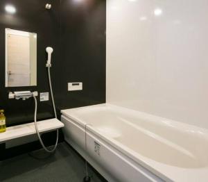 鹿児島市にあるROI SPACE 鹿児島のバスルーム(鏡付き白いバスタブ付)
