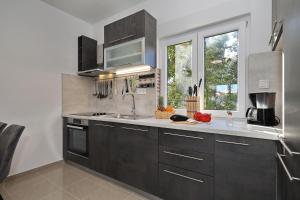 een keuken met zwarte kasten, een wastafel en een raam bij Apartments Oliva in Vrsi