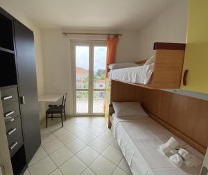a room with two beds and a desk and a window at Orange Apartment in Marina di Massa