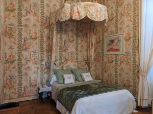 una camera con un letto in una stanza con carta da parati di Maison d'hôtes - Hôtel particulier de Jerphanion Cambacérès a Le Puy en Velay