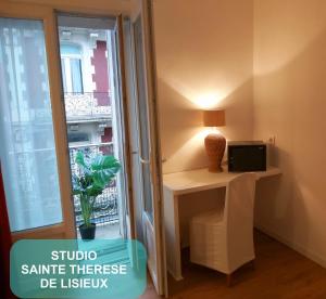 um quarto com uma mesa com um candeeiro e uma janela em Au Berceau de Bernadette em Lourdes