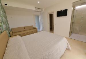 um quarto com uma cama branca e um sofá em L'OLEANDRO Room's - Suite & Spa da Giuseppe em Gonnosfanàdiga