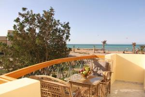 una mesa y sillas en un balcón con vistas a la playa en Villa Anna & Snake en Hurghada