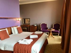 een hotelkamer met een bed en twee paarse stoelen bij Purbeck House Hotel & Louisa Lodge in Swanage