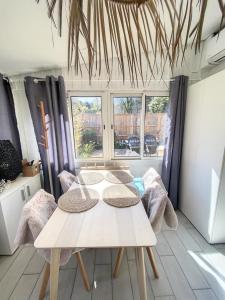 una mesa y sillas en una habitación con ventanas en le nichoir classé 3 étoiles maison 4pers climatisée 2pieces Audenge Bassin d'Arcachon en Audenge