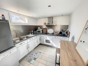 a kitchen with white cabinets and a sink and a table at le nichoir classé 3 étoiles maison 4pers climatisée 2pieces Audenge Bassin d'Arcachon in Audenge