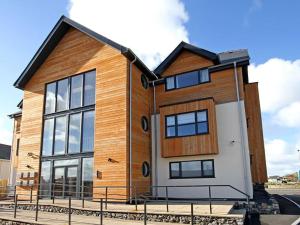 a large wooden house with windows on a street at 1 Y Bae - Top Floor Apartment in Trearddur