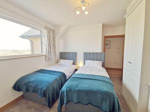 two beds in a room with a window at 1 Y Bae - Top Floor Apartment in Trearddur