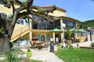 Casa amarilla con patio y árbol en Au Grand Bonheur, en Bessèges