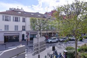 una strada di città con auto parcheggiate di fronte agli edifici di Loft hyper centre Vincennes RER a 5 mn freePark a Vincennes