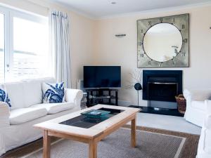 a living room with white furniture and a mirror at Westpoint in Wadebridge