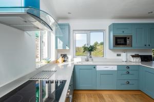 a kitchen with blue cabinets and a window at Westpoint in Wadebridge