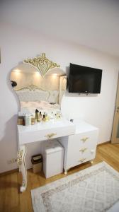 een slaapkamer met een bed, een wit bureau en een televisie bij Casa Ryn Navodari in Năvodari