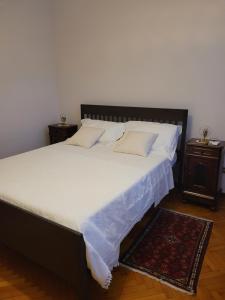 um quarto com uma cama grande com lençóis brancos e um tapete em Casa Perugina em Montagnana
