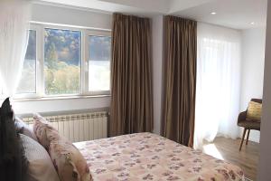 um quarto com uma cama e duas janelas em Central Park View Sinaia em Sinaia