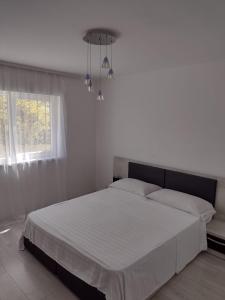 um quarto com uma cama com lençóis brancos e um lustre em Apartment Rezidence em Suceava
