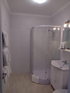 a white bathroom with a shower and a sink at Apartment Rezidence in Suceava