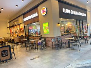 a woman sitting in front of a restaurant with tables and chairs at Central of Sunway Town; 8 PAX in Petaling Jaya