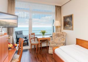 a hotel room with a bed and a table and a window at Strandhotel Monbijou GmbH garni in Westerland