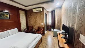 Schlafzimmer mit einem Bett, einem Schreibtisch und einem TV in der Unterkunft Khách sạn Rosy Việt Trì in Việt Trì