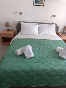 uma cama com duas toalhas num cobertor verde em Lefkothea Hotel em Kamari