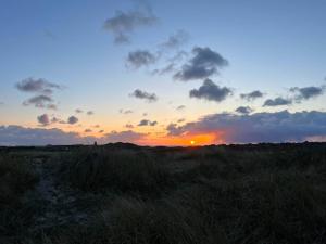 einen Sonnenuntergang auf einem Feld mit Sonnenuntergang in der Unterkunft Ferienwohnung Glück in Westerland