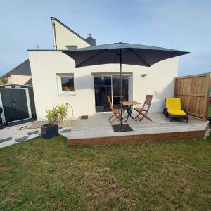 una terrazza con ombrellone e due sedie e un tavolo di Studio avec terrasse et jardin à 100 m de la plage a Ploemeur