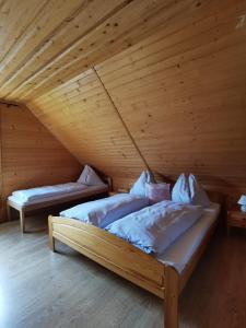 two beds in a room with a wooden ceiling at Drevenica Západné Tatry in Žiar