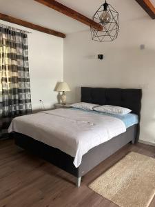 a bedroom with a large bed with a black headboard at Tina in Tekija