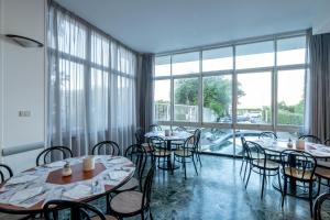 a dining room with tables and chairs and large windows at Real Park Hotel in Cavi di Lavagna