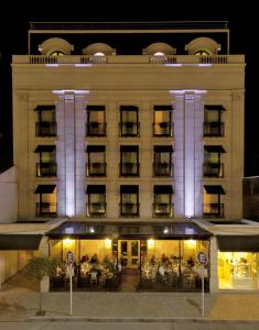 un grand bâtiment avec des personnes assises à l'extérieur la nuit dans l'établissement Hotel Sainte Jeanne, à Mar del Plata