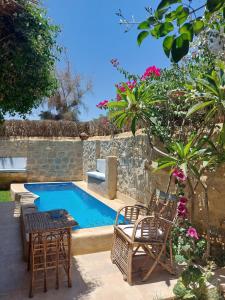 un patio trasero con piscina, sillas y mesa en Barefoot by Barefoot in Tunis, en ‘Izbat an Nāmūs